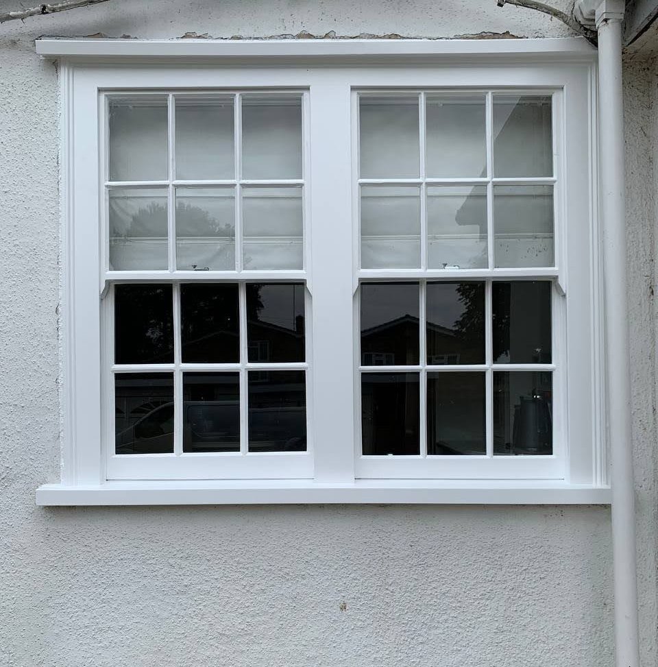 Two six-over-six sashes side by side in one white frame on a rendered wall