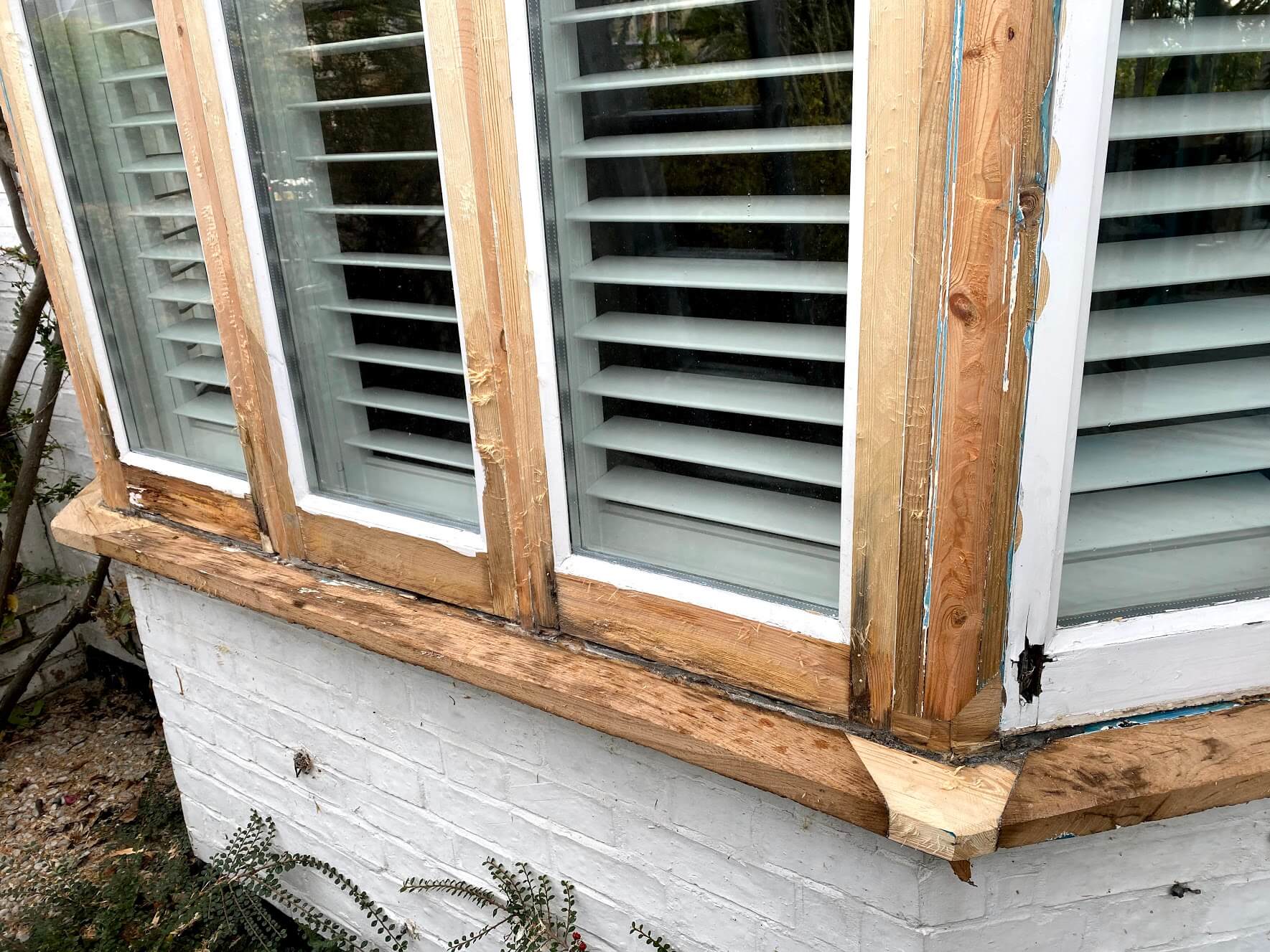 Timber bay casement window stripped to bare wood, with a new piece of timber spliced into the sill corner