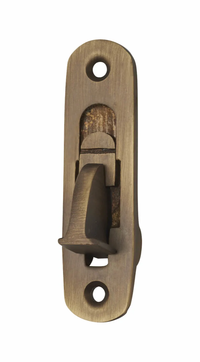 An antique brass sash window restrictor with a spring tongue