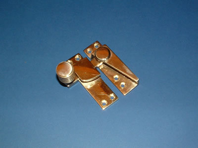 A brass straight-arm sash fastener with a reeded knob
