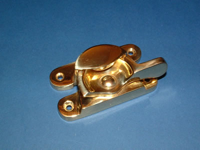 A polished brass Fitch sash fastener with its curved cam and keeper