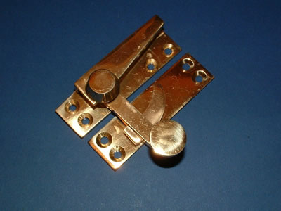 A polished brass quadrant-arm sash fastener with its curved keeper