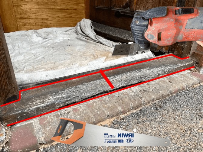 An old door sill marked in red where it is to be cut: once across the middle and along the edges, a hand saw beside it