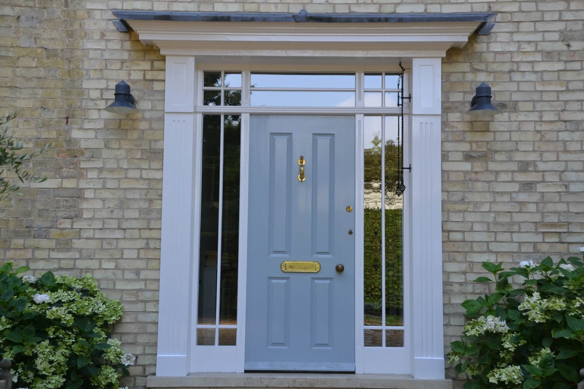 Victorian front door painted pale blue with a brass knocker and letter plate, glazed side lights and white surround