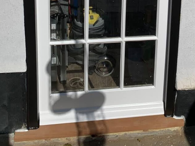 A weathered mahogany sill under a white glazed door