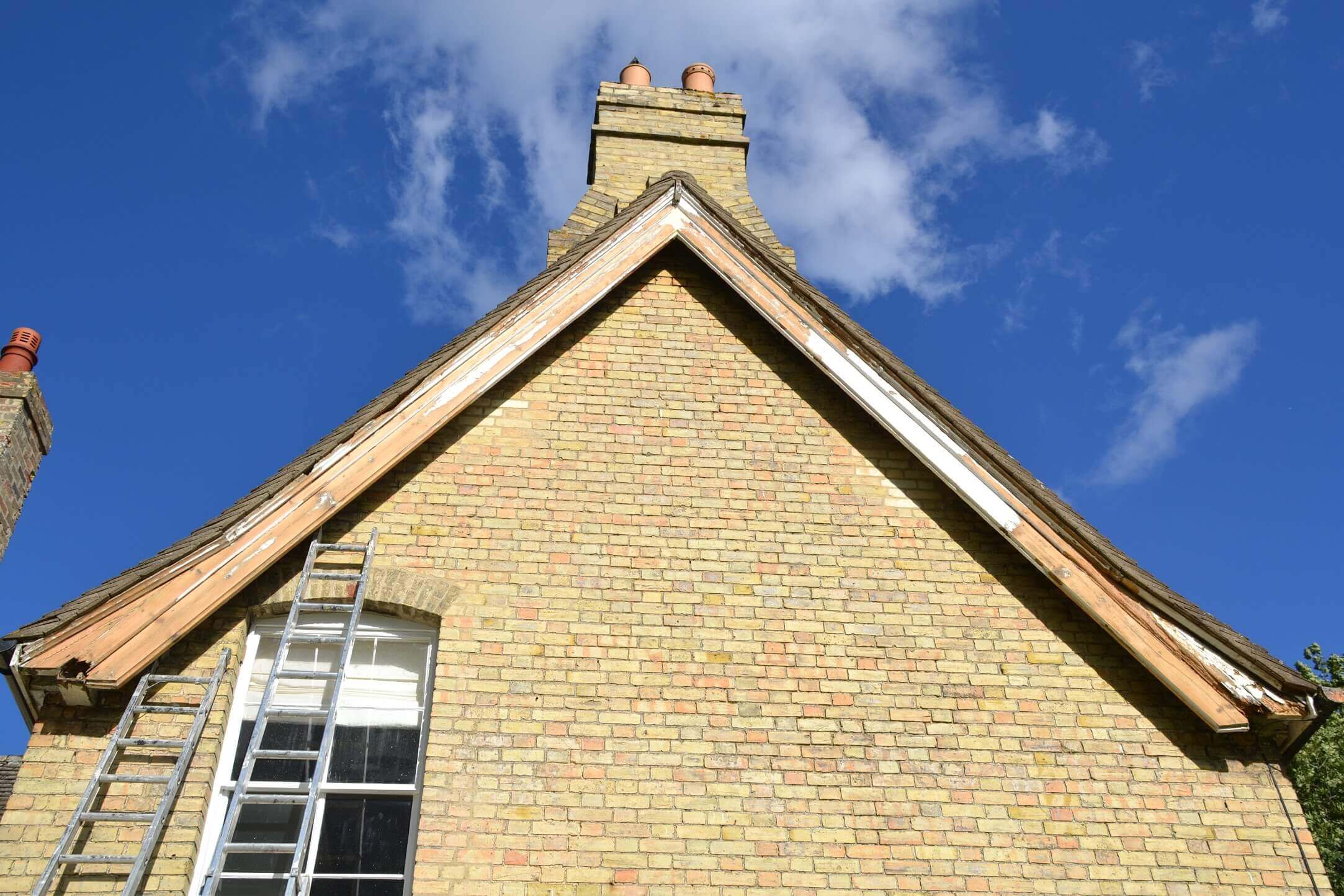 Brick gable with its bargeboards stripped back and ladders up to a first-floor window