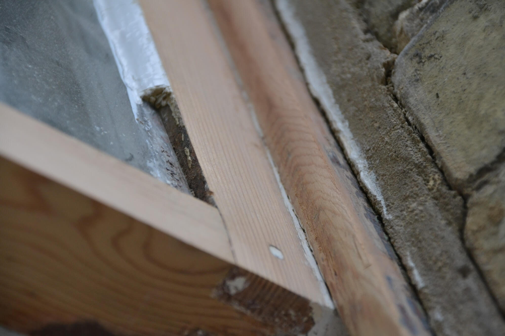 Close-up of a sash sanded to bare wood, with the glazing putty missing along the edge of the glass