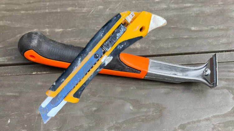 A scraper and a utility knife on decking