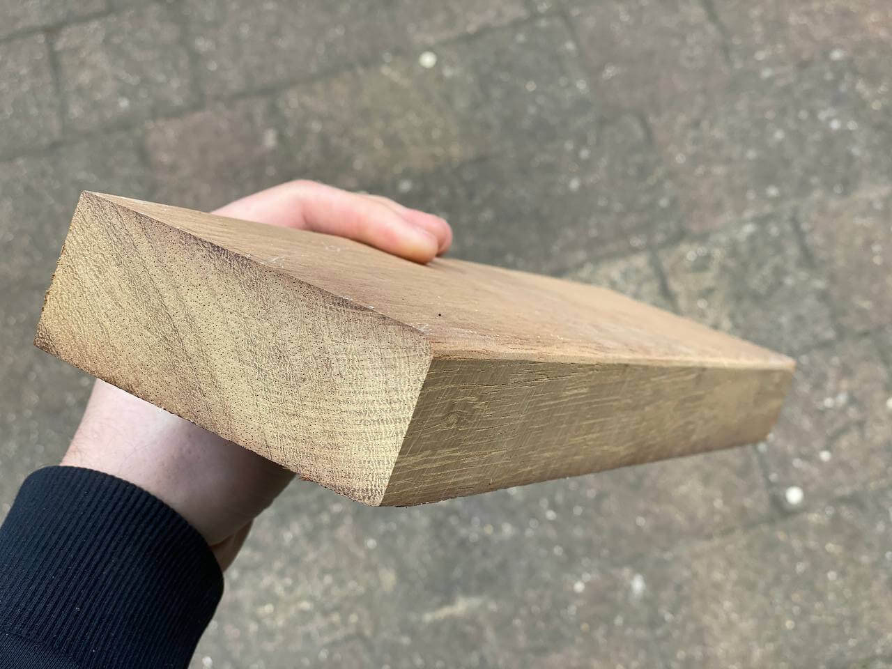 A piece of planed hardwood for a new door sill held in a hand