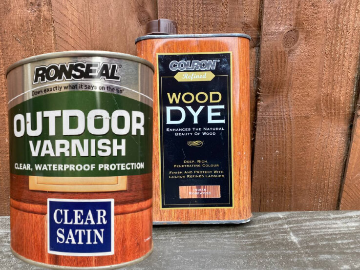 A tin of Ronseal Outdoor Varnish clear satin beside a tin of Colron wood dye