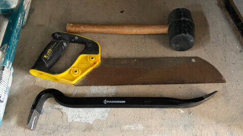 A crowbar, a hammer and a hand saw on decking