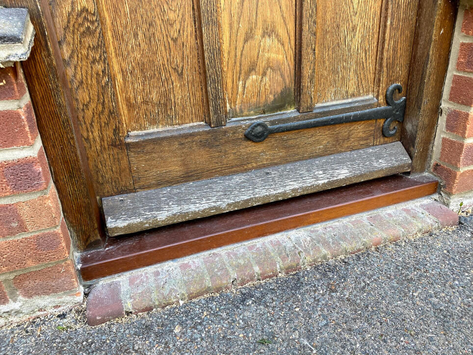 The finished new door sill, dyed dark and varnished, under the old wooden front door