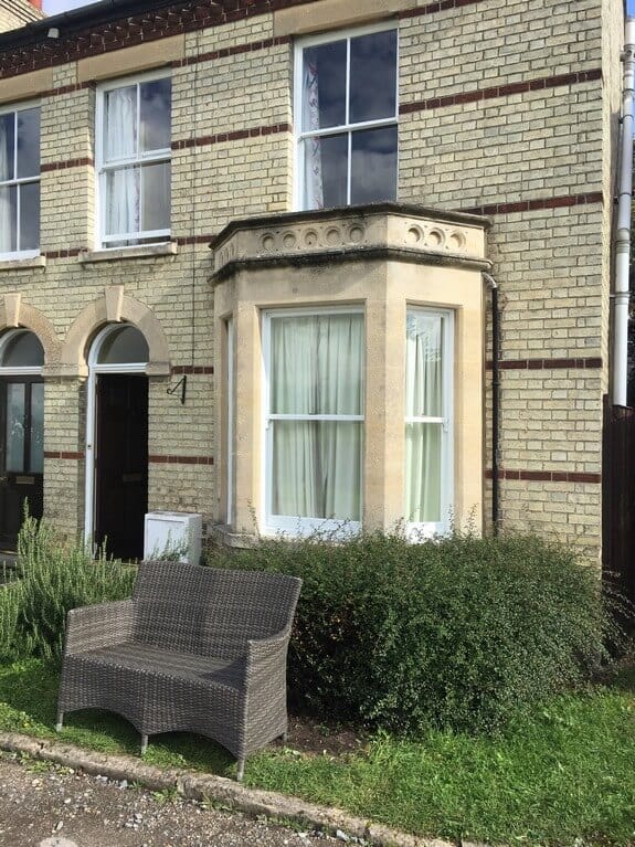 Victorian yellow-brick house with red brick bands, a stone bay window, white sash windows and arched doorways