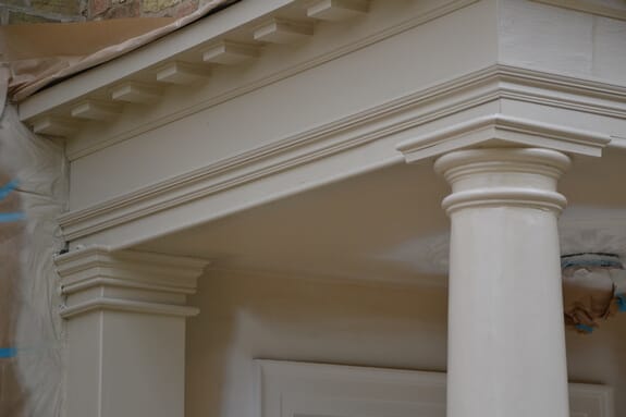 Close-up of the repainted porch cornice with dentil blocks above a column capital