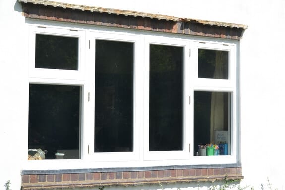 Wide white-painted timber casement window: two tall centre lights flanked by lights with top lights, in white render