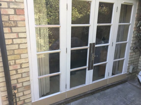 Timber patio doors with new, unpainted timber along the bottom rails of all four leaves