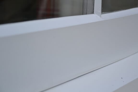 Close-up of smooth white paint on a window's bottom rail and sill
