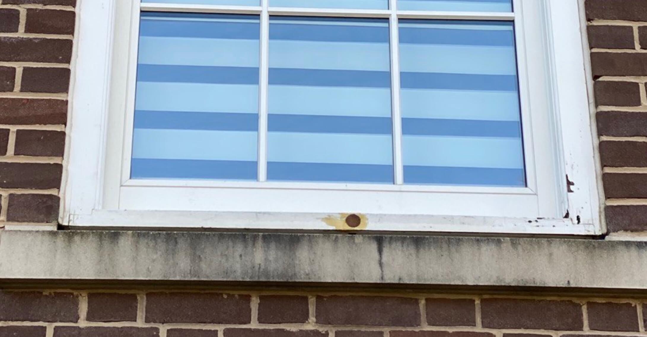 A refurbished sash window in a brick building with blue and white stripes.