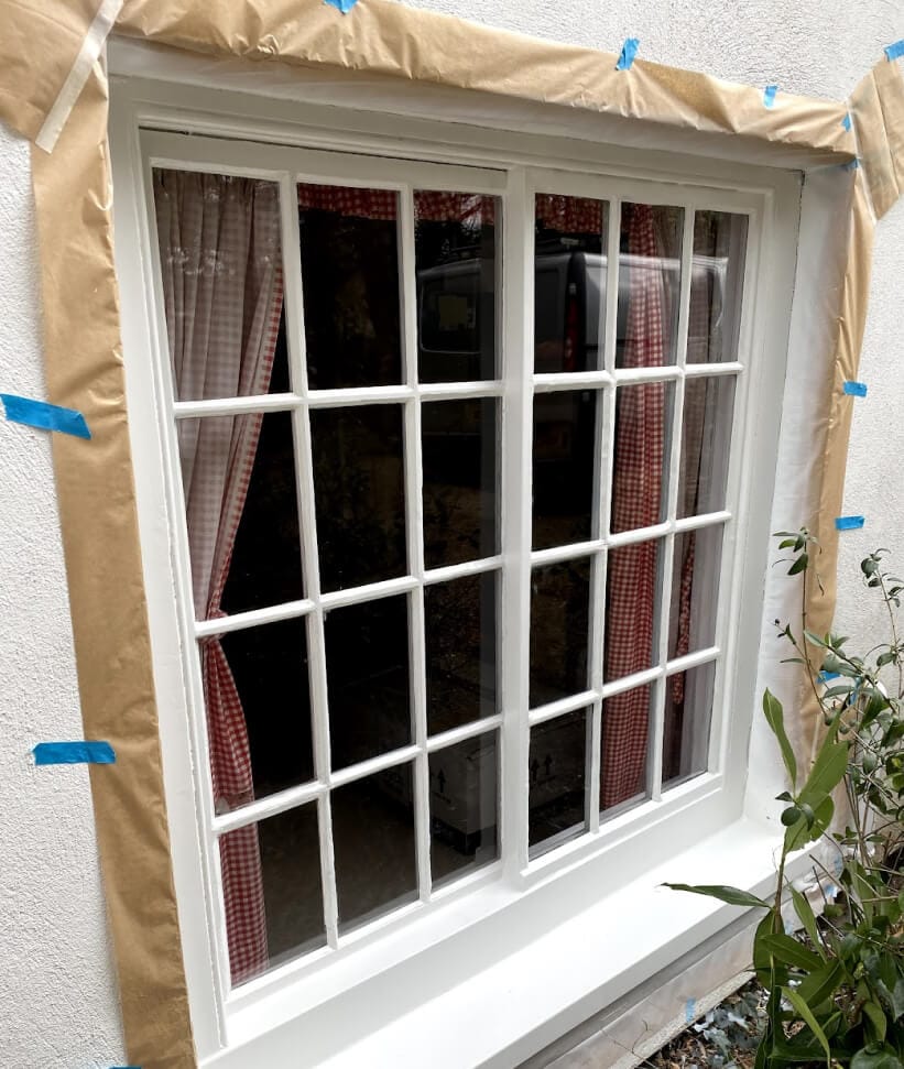 A Yorkshire sash window of two sashes side by side, twelve panes each, masked with paper and blue tape for painting