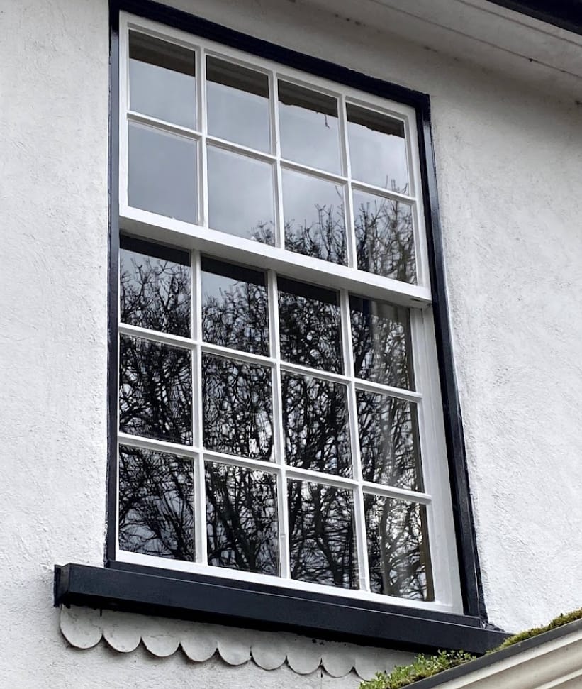 A sash window with eight panes in the upper sash and twelve in the lower, in a black frame
