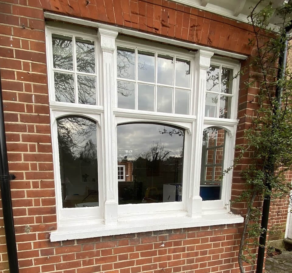 Three sashes side by side in a red-brick wall: small panes in the upper sashes, single arched-top panes below
