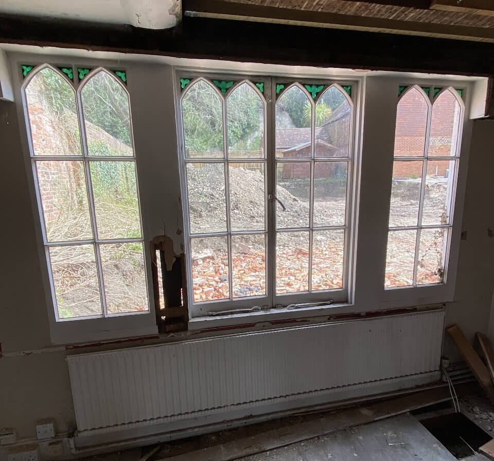 Three sashes with pointed Gothic heads and green glass corners, seen from inside during restoration