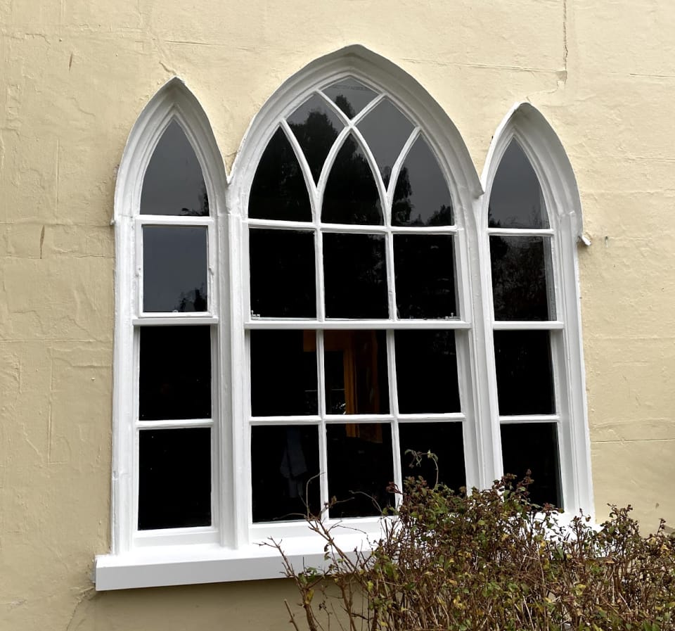 A Gothic sash window with pointed heads and pointed upper panes in a cream wall