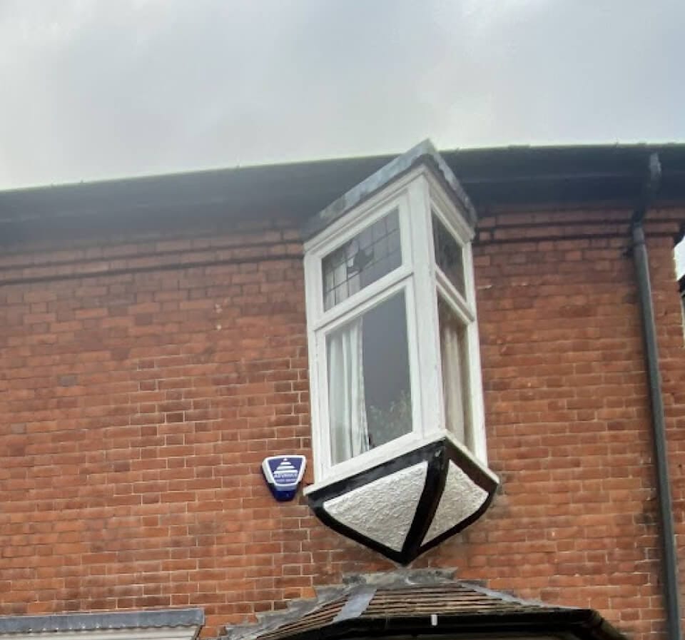 A small oriel window on brackets on the upper floor of a red-brick house