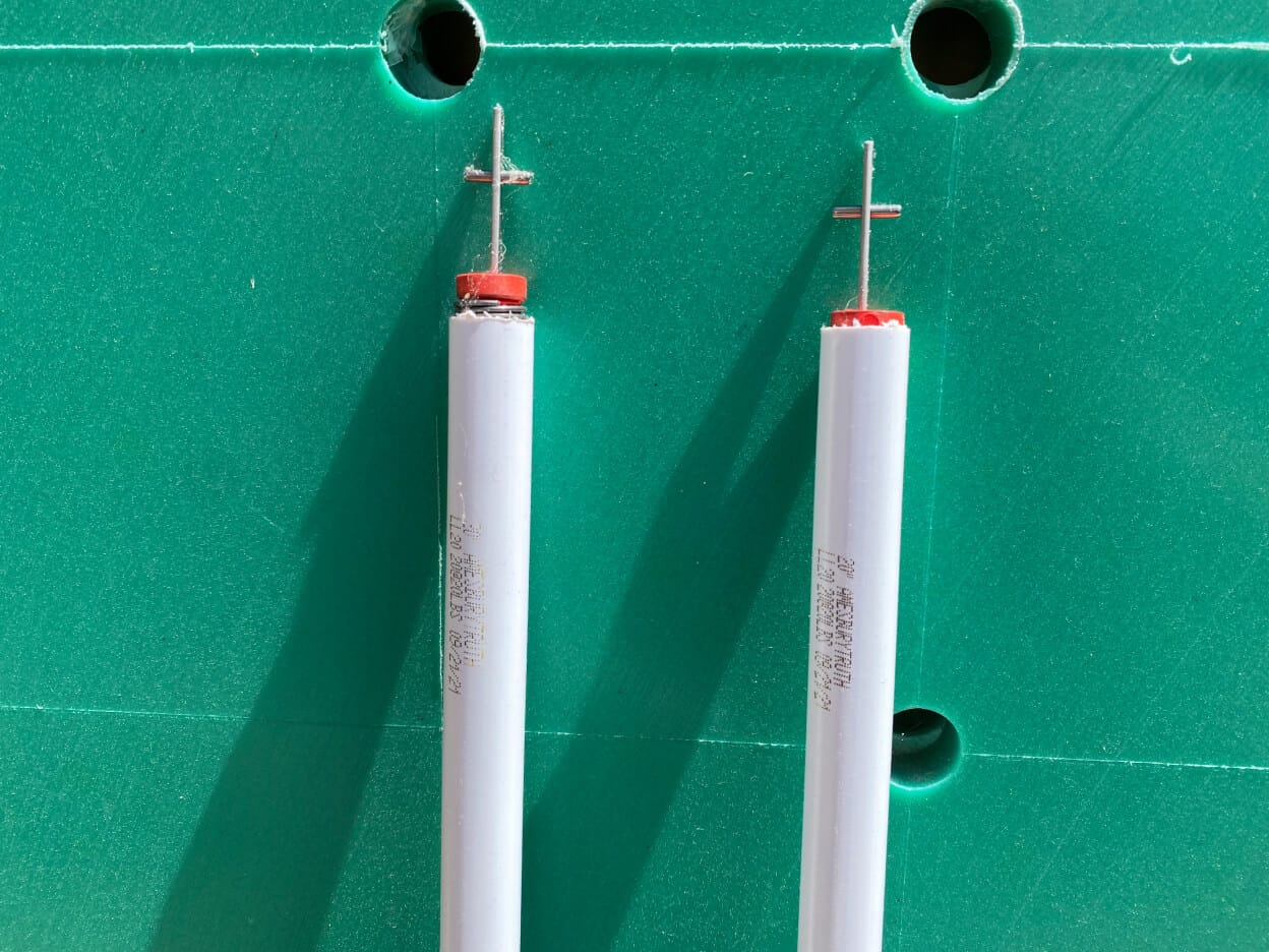Two spiral spring balances for a sash window lying on a green workbench