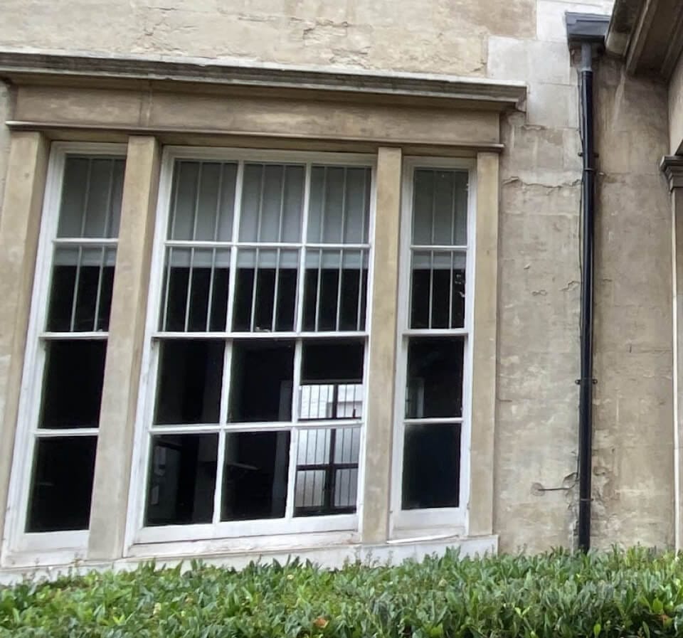 A three-part sash window divided by stone mullions in a stone front