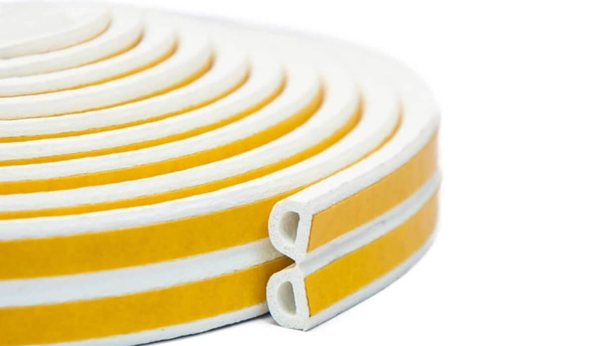 Coil of white self-adhesive draught-seal strip with yellow backing tape and a hollow profile at the cut end